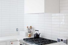 a serene white kitchen with a white skinny tile backsplash, copper fixtures and a white hood is very welcoming
