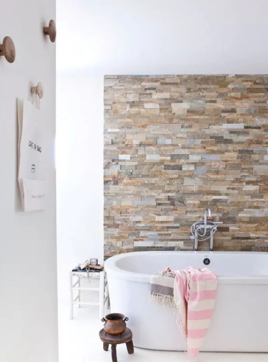 an earthy colored faux stone accent wall is a gorgeoys way to spruce up a neutral contemporary bathroom