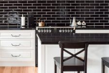 19 a white farmhouse kitchen with black glossy tiles, a black hood and countertops plus black stools
