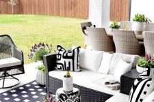 22 a patio with black wicker chair and black and white upholstery and a black and white printed stool plus blooms