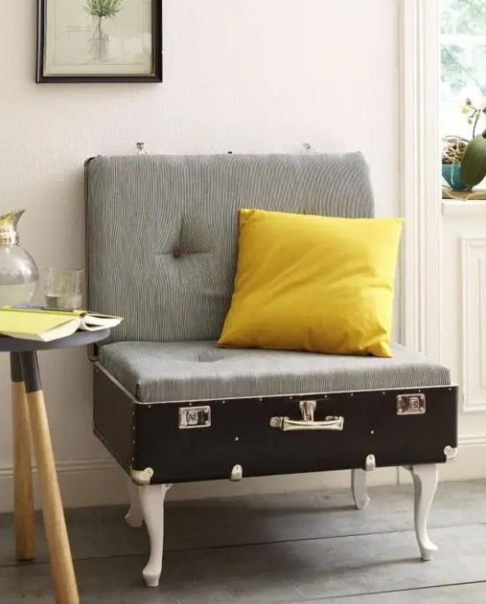 a lovely chair made of a vintage suitcase placed on legs, with cushions for comfortable sitting and a bright pillow - such a cool DIY