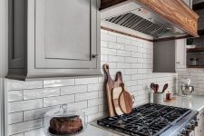 23 glossy off-white tiles on the backsplash are highlighted with black grout and perfectly match the grey cabinets