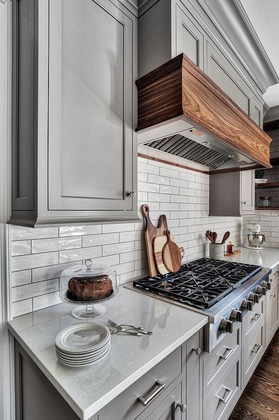 glossy off white tiles on the backsplash are highlighted with black grout and perfectly match the grey cabinets