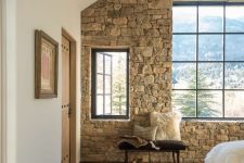 25 a cabin bedroom with a stone accent wall, an attic roof, modern furniture and a gorgeous mountain view is very welcoming