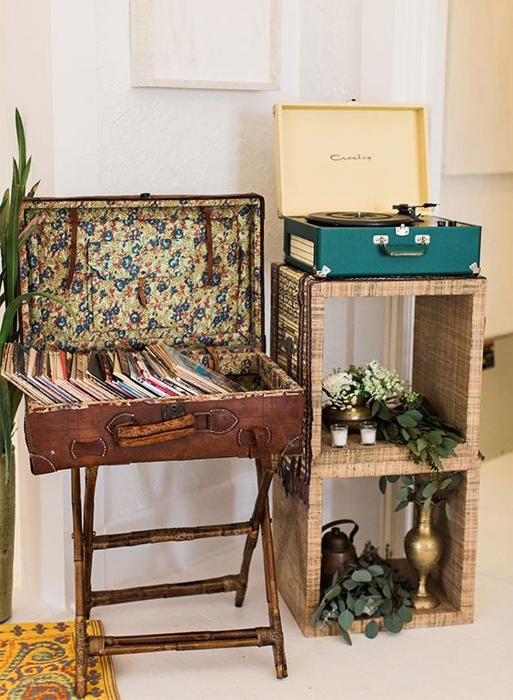 a stand with a turn-table and a vintage suitcase placed on legs for storing vinyl are a great combo for a vintage-inspired space