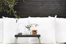 27 a Scandinavian terrace with black walls, a black and white sofa, a small black table for serving drinks and food
