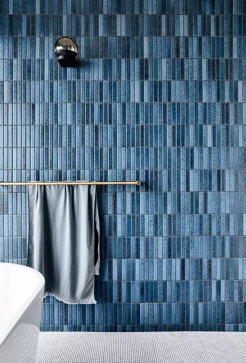 a chic contemporary bathroom with a grey floor, a blue navy skinny tile wall and brass touches looks chic