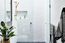 29 a chic contemporary bathroom with grey tiles on the floor and white skinny tiles on the walls plus niches
