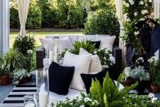 29 a stunning black and white terrace with black wicker furniture, a stone bench, lots of greenery, blooms and candles