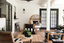 31 a stylish terrace with a brick floor, stained furniture, black and white upholstery, potted greenery and a low coffee table
