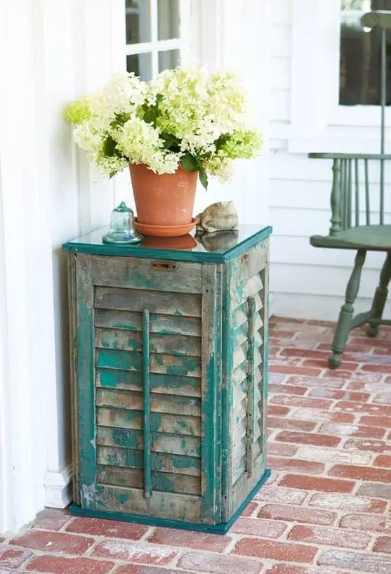 an outdoor side table of old shutters and a couple of wooden planks, the aged look fo the shutters is highlighted