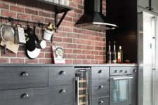 35 a sleek black kitchen with a glossy black hood and a red brick accent wall that doubles as a backsplash is lovely