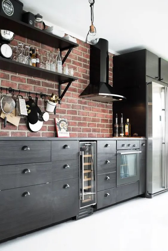 a sleek black kitchen with a glossy black hood and a red brick accent wall that doubles as a backsplash is lovely