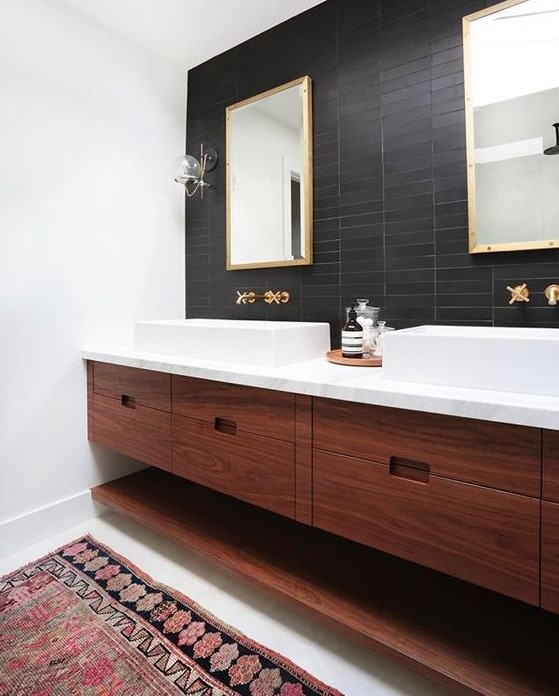 a mid century modern bathroom with black skinny tiles on the accent wall that contrast white sinks