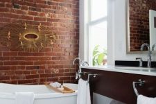 38 a chic bathroom done in white and with contrasting touches – a red brick wall and a rich toned vanity