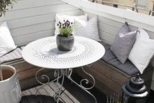 39 a cool Scandinavian balcony with a corner sofa with pillows and cushions, candle lanterns, potted blooms and greenery and a white table