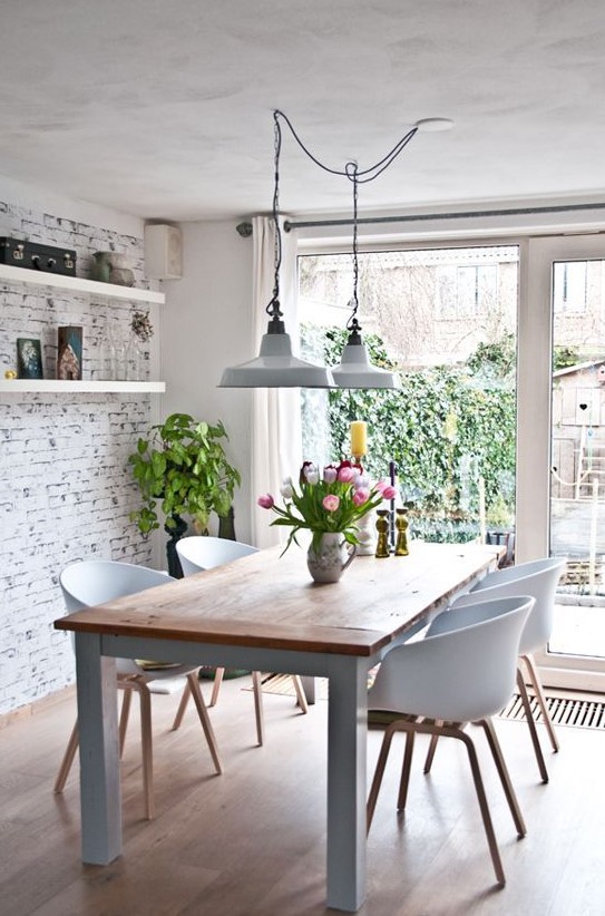 a modern Nordic dining room with a whitewashed brick wall, a modern dining set and vintage lamps and potted plants
