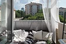 41 a monochromatic balcony with dark furniture, printed textiles, sheer curtains and potted greenery