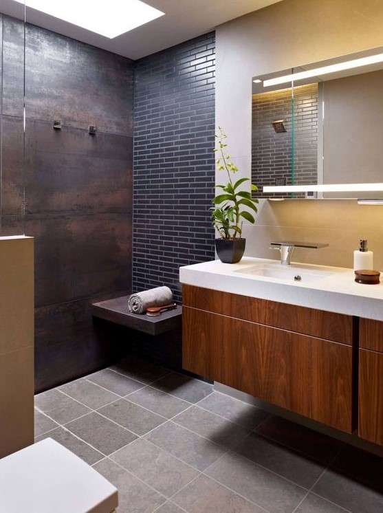 a shower space done with an aged metal wall and a navy skinny tile accent wall plus a floating bench of metal