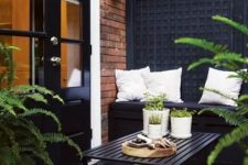 43 a Nordic balcony with a black wall, a black built-in bench and a wooden table, a printed chair and potted greenery to refresh the space