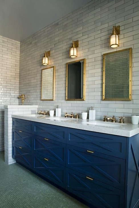 an art deco bathroom with marble skinny tiles, a bright blue vanity and brass touches here and there
