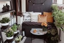 51 a tiny monochromatic balcony with black and white walls, black furniture, potted greenery and blooms and various pillows and rugs