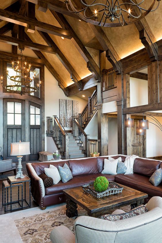 a barn living room with dark stained beams, a brown leather corner sofa, a stained table and a printed sofa