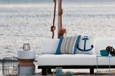 a beach patio with white upholstered furniture, neutral rugs, some rope, seaside pillows and candle lanterns