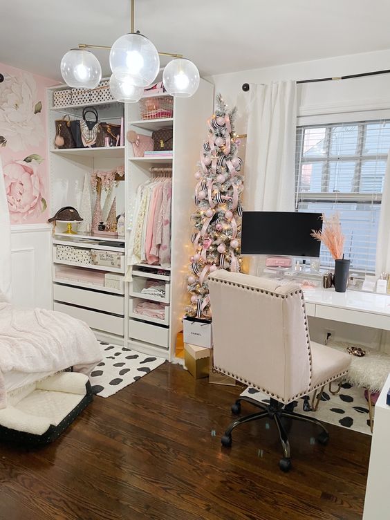 a beautfiful and delicate glam cloffice with a white storage unit with drawers, a white desk and a creamy chair, a Christmas tree with pink decor