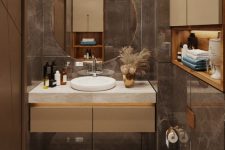 a beautiful and exquisite bathroom clad with brown marble tiles and white ones, a built-in vanity with a round sink and a round mirror