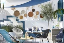 a blue seaside patio with rugs, bold woven chairs and stools, decorative plates, lamps and potted plants
