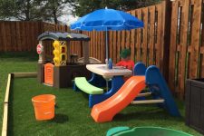 a bright and fun kids’ play space with a colorful dining set with an umbrella, a mini house, a turtle sandbox and a slide