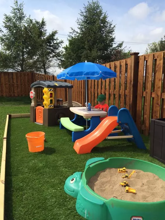 a bright and fun kids' play space with a colorful dining set with an umbrella, a mini house, a turtle sandbox and a slide