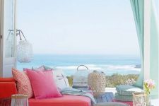 a bright beach deck with colorful furniture, cushions and textiles, candle lanterns and turquoise curtains and a gorgeous sea view