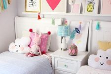 a bright shared girls’ bedroom with a ledge with bright artwork, two matching beds with bright bedding and fun pillows