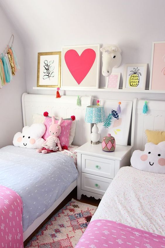 a bright shared girls' bedroom with a ledge with bright artwork, two matching beds with bright bedding and fun pillows