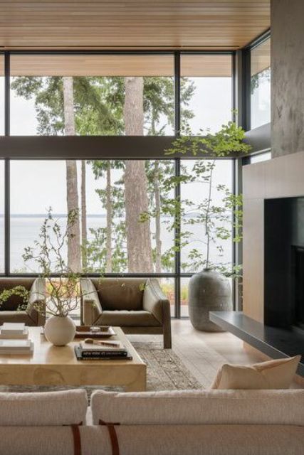 a calm and soothing living room done in natural colors, with leather chairs and a stone coffee table plus a floor to ceiling window to enjoy the views
