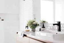 a chic Scandinavian bathroom with white hex and square tiles, a floating wooden vanity and black touches here and there