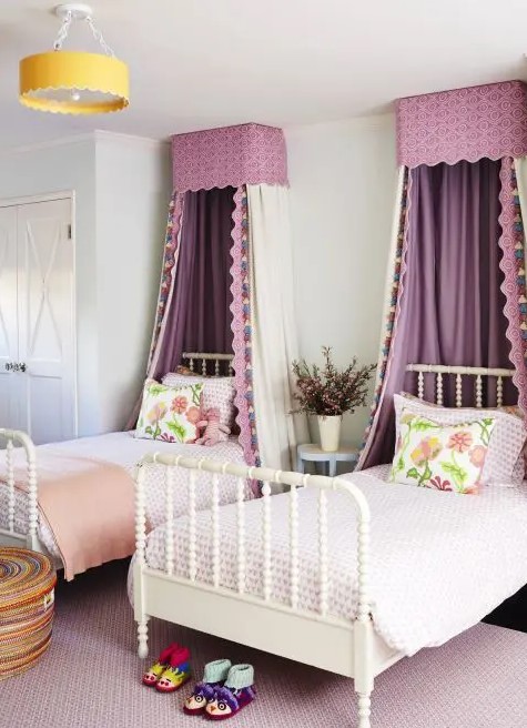 a chic and stylish shared girls' bedroom with white vintage beds, lilac and peachy bedding, purple canopies, a built-in wardrobe and a woven basket for storage