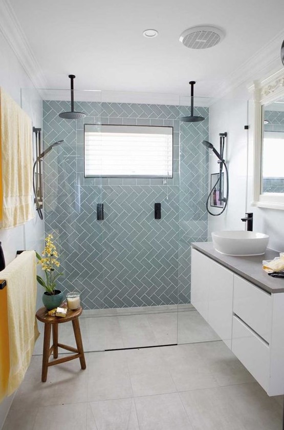 a chic tiny bathroom with light blue tiles, a floating white vanity with a cocnrete countertop, black fixtures and bold linens