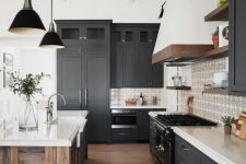 a contemporary barn kitchen with graphite grey shaker style cabinets, white stone countertops, a reclaimed wood kitchen island and black lamps