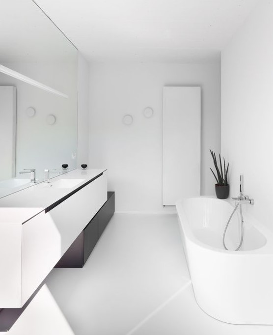 a contrasting minimalist bathroom with a floating vanity, a mirror wall, white appliances and built in lights