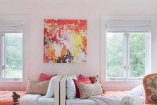 a cool and bold shared girls’ bedroom with white beds, a bright chair, a colorful artwork and bedding, an orange pendant lamp and a toy