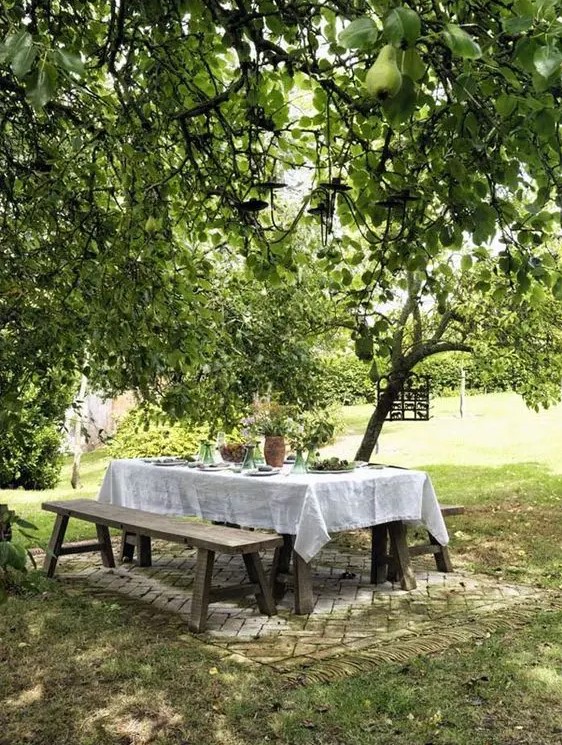 a cozy and simple dining space right in the garden, with simple wooden dining furniture   a table and benches