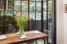a dining space located in a glazed floor to ceiling niche gives a feel of eating outdoors anytime, whatever the weather is