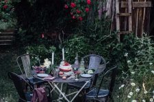 a little garden eating nook with a metal table and some meatching chairs plus blankets created in blooming surroundings