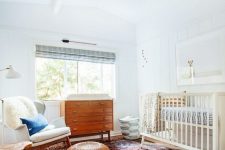 a mid-century modern nursery with a neutral crib and printed bedding, a bold printed rug, a rocker chair with a pillow and a stained dresser