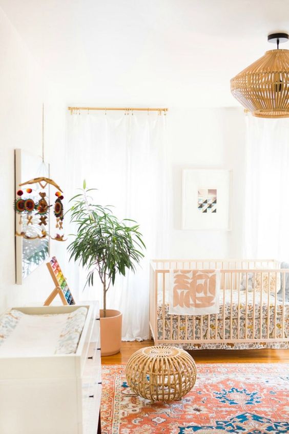 a mid century modern nursery with neutral walls, a bold printed rug and bedding, a wooden pendant lamp and a pouf and a white dresser