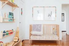 a mid-century modern nursery with stained open shelves, a wooden crib, a bright printed rug, printed bedding, artwork and bright decor and toys