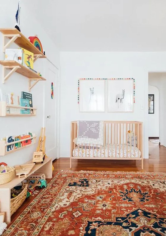 a mid century modern nursery with stained open shelves, a wooden crib, a bright printed rug, printed bedding, artwork and bright decor and toys